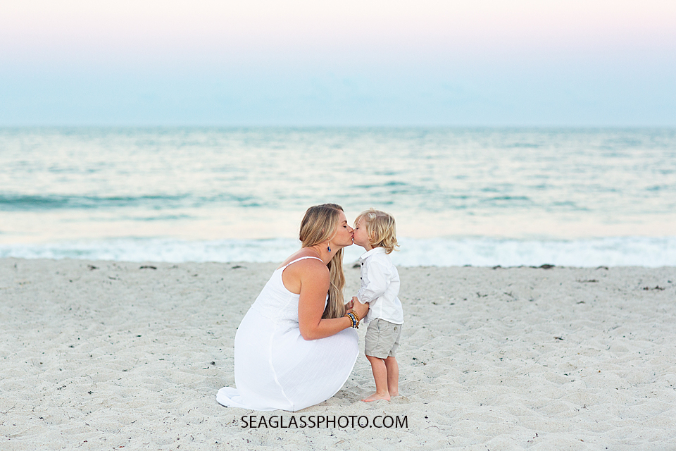 Little boy gives his mom a kiss on the beach during their family photoshoot in Vero Beach Florida