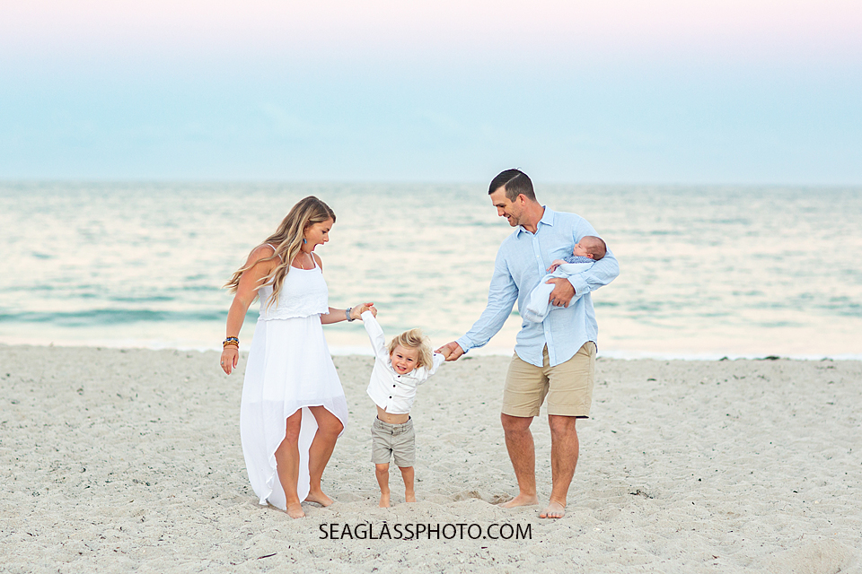 Little boy did a full flip and his parents loo very surprised and happy for him on the beach during their family photoshoot in Vero Beach Florida