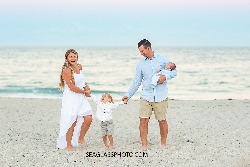Family laughs as they walk on the beach during their family photoshoot in Vero Beach Florida