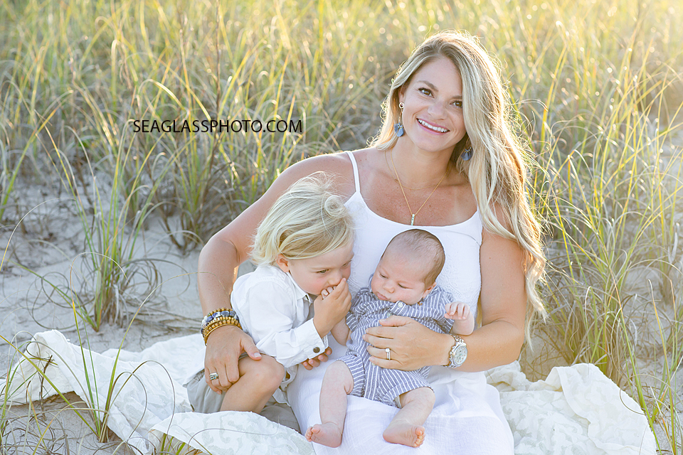 Mother and her two sons sitting in the dunes on the beach during their family photoshoot in Vero Beach Florida
