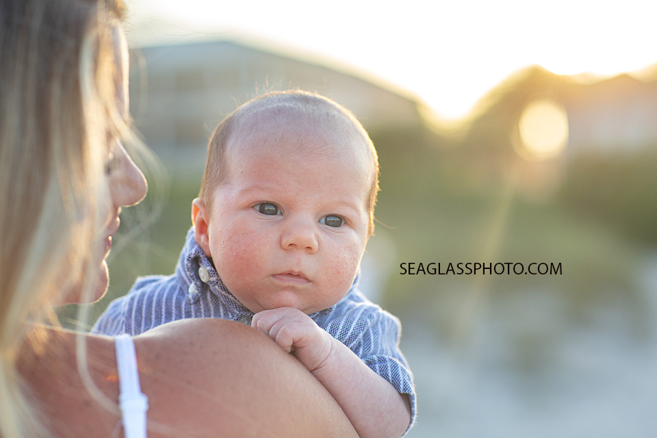 Close up of baby boy looking over his moms shoulder on the beach during their family photoshoot in Vero Beach Florida