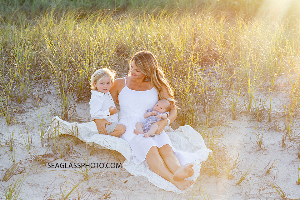 Mom looks at her son while sitting in the dunes on the beach during their family photoshoot in Vero Beach Florida
