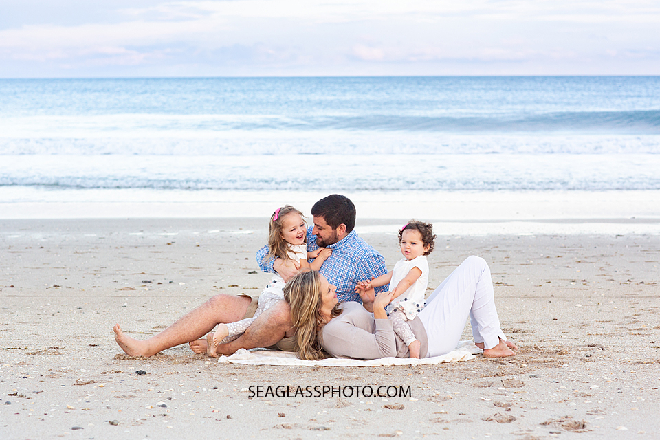 Family of four laying on the beach during their family photo shoot in Vero Beach Florida