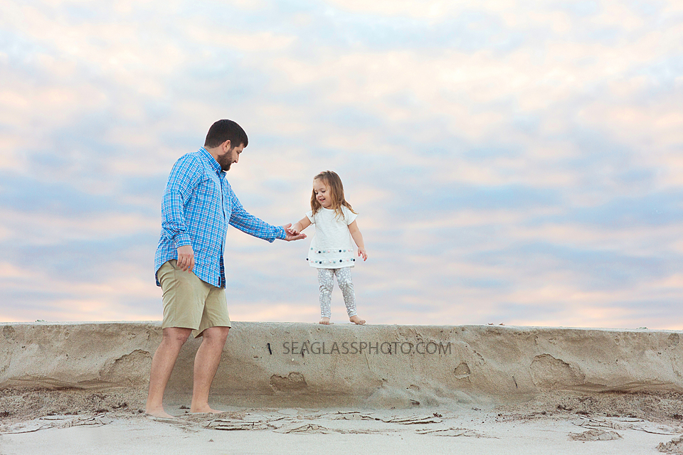 Dad helps his daughter down a step on the beach during their family photo shoot in Vero Beach Florida
