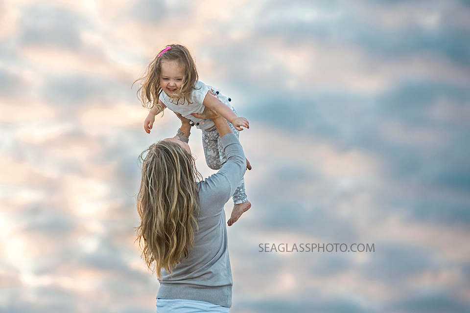 Mom plays airplane with her daughter on the beach during their family photo shoot in Vero Beach Florida