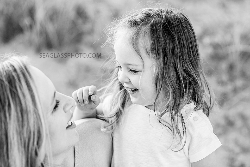 Black and white photo of a daughter and mother smiling at each other during their family photo shoot in Vero Beach Florida