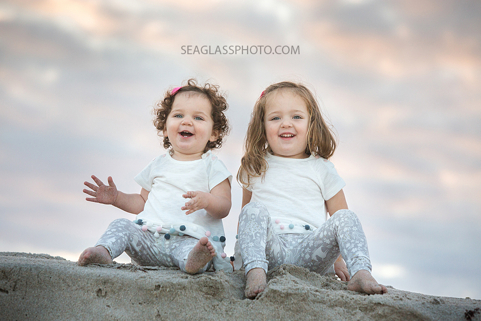 Sisters sit on the beach and smile on the beach during family photos in Vero Beach Florida