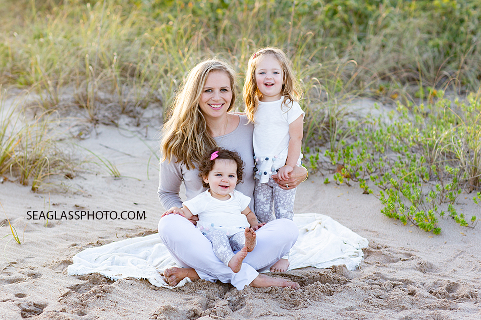 A Beautiful mom with her two daughters sitting on the beach during their family photo shoot in Vero Beach Florida