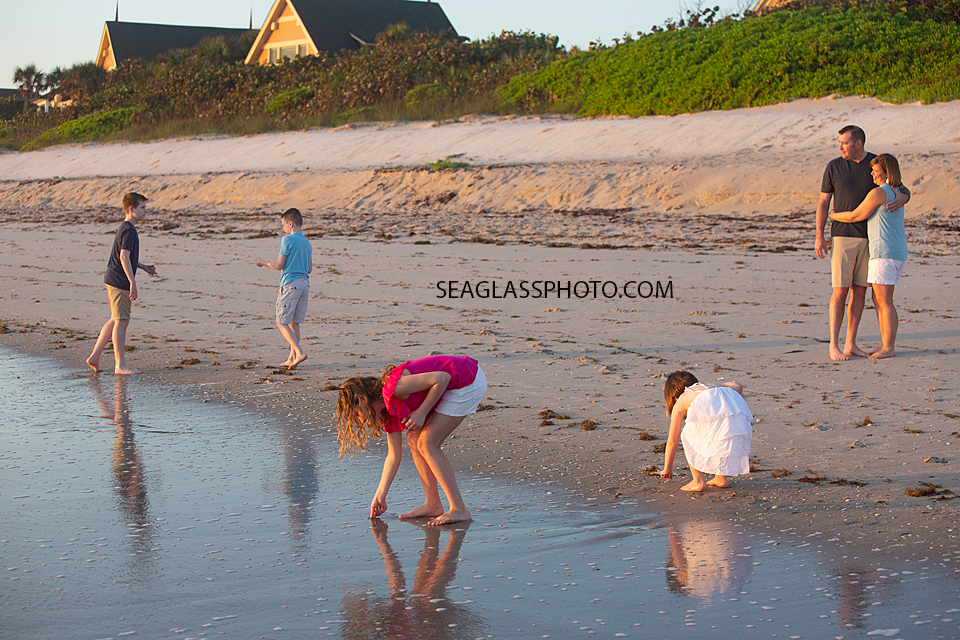 Parents watch as their children play on the beach with each other during a family photoshoot in Vero Beach Florida