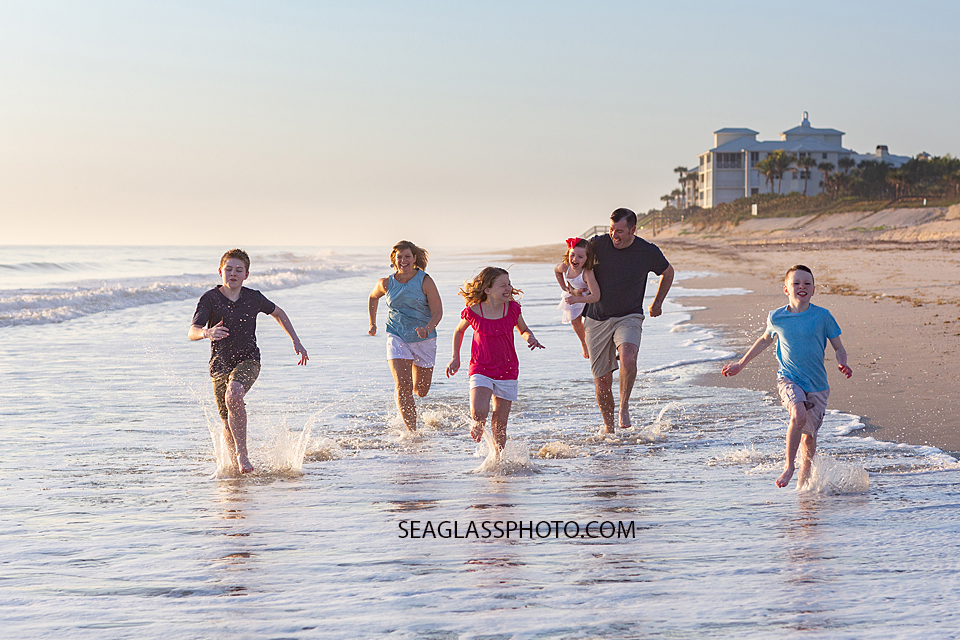 Family races in the water to see who is the fastest looks to me like its the youngest boy during a family photoshoot in Vero Beach Florida