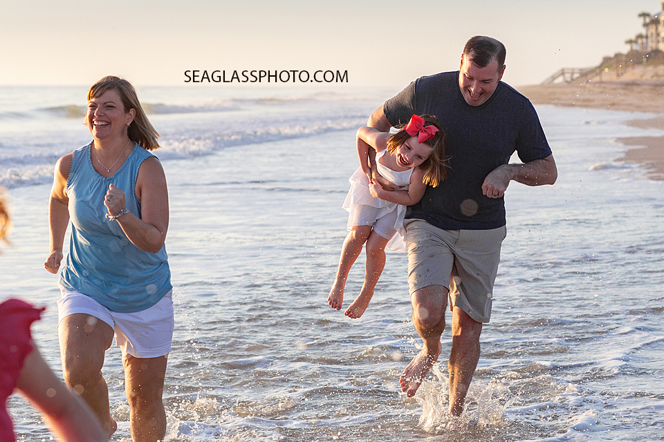 Father carries his youngest child so she doesn't get left behind in the race during a family photoshoot in Vero Beach Florida