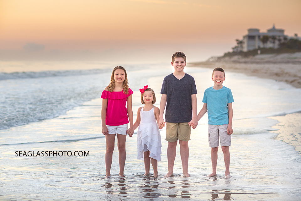Brothers and sisters holding hands on the beach during a family photoshoot in Vero Beach Florida