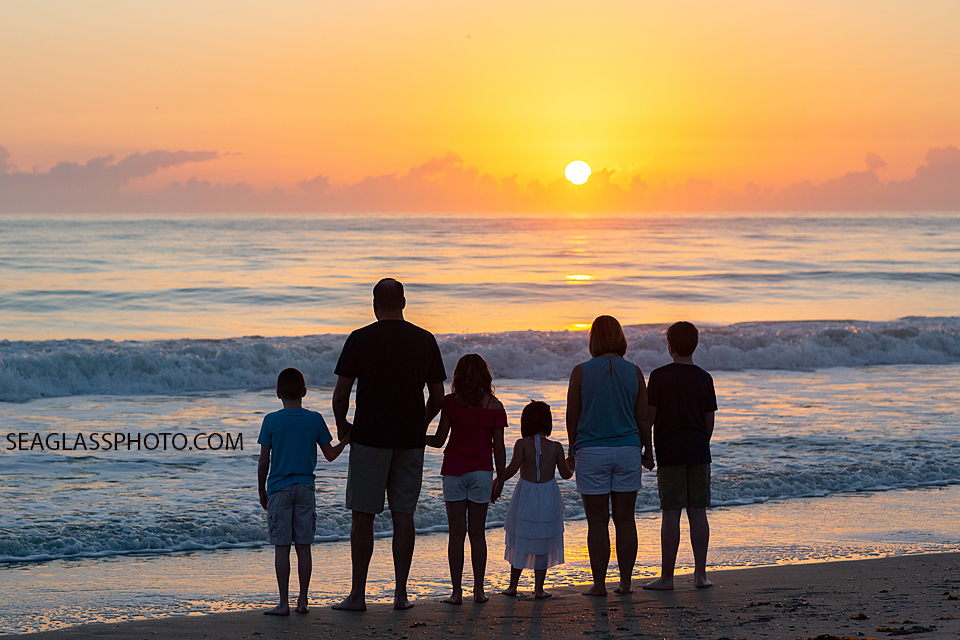 Family looks out over the ocean to watch the sunrise during a family photoshoot in Vero Beach Florida