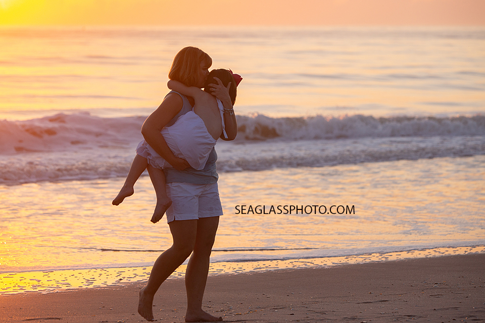 Mom walking and holding her daughter on the beach during a family photoshoot in Vero Beach Florida