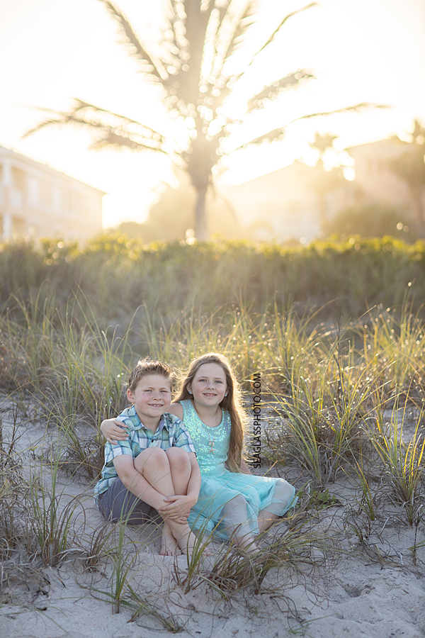 Brother and sister sit together in the sand dunes during a family photoshoot in Vero Beach Florida