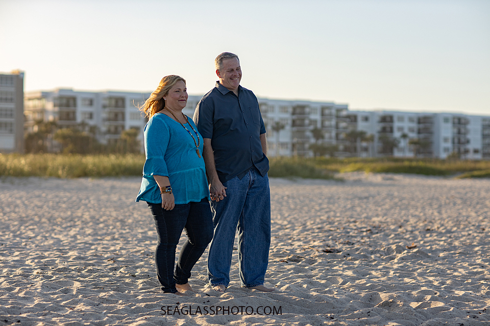 Mom and dad walking on the beach while they watch their kids play during a family photoshoot in Vero Beach Florida