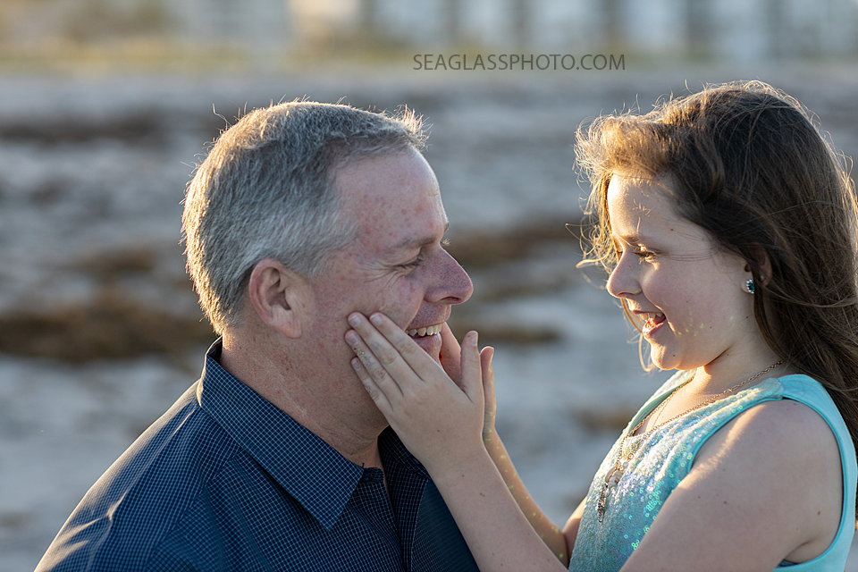 Daughter plays with her dads cheeks during a family photoshoot in Vero Beach Florida