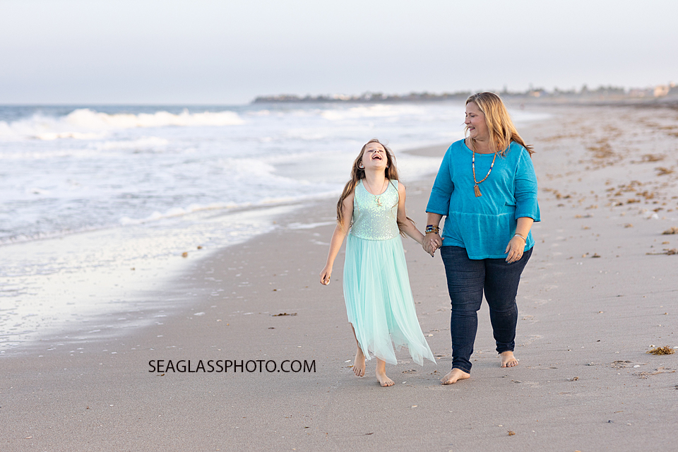 Mother and daughter walk on the beach and laugh during a family photoshoot in Vero Beach Florida