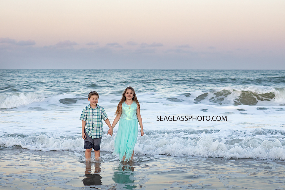 Brother and sister walking in the water on the beach during a family photoshoot in Vero Beach Florida