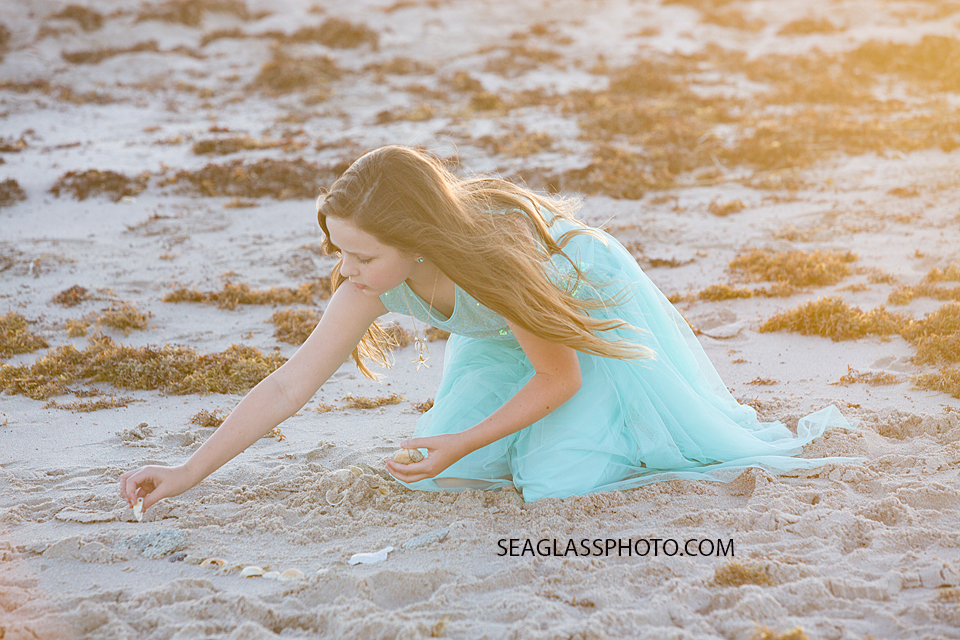 Beautiful girl making art with shells on the beach during a family photoshoot in Vero Beach Florida