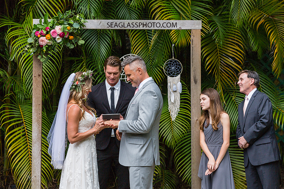 Bride slips wedding band on her grooms finger during their ceremony in Vero Beach Florida