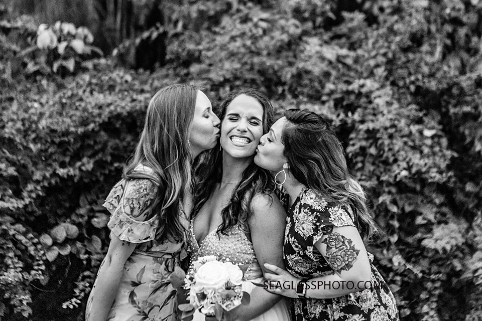 Black and White Bridesmaids kiss the bride on her cheek following her wedding in Vero Beach Florida