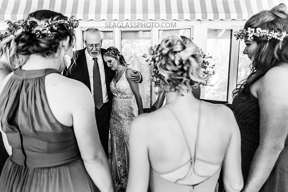 Black and white photo of a bride and her wedding party praying before the ceremony in Vero Beach Florida