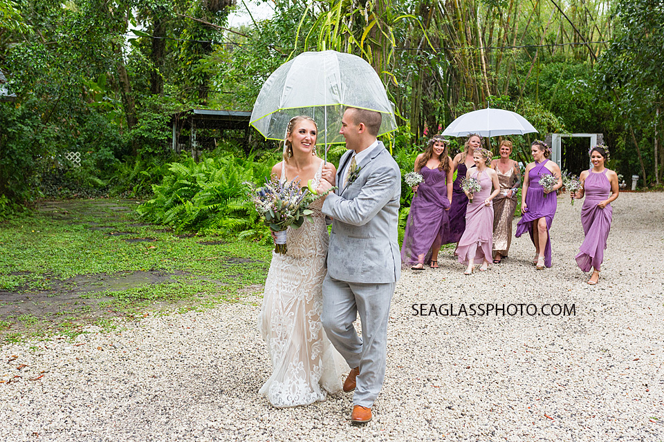 Bride and groom huddle under an umbrella after the ceremony in Vero Beach Florida