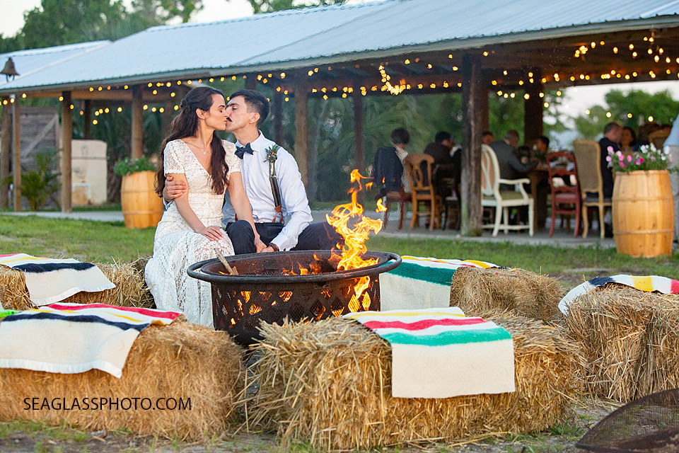 Husband and Wife sit by the camp fire during their reception in Vero Beach Florida