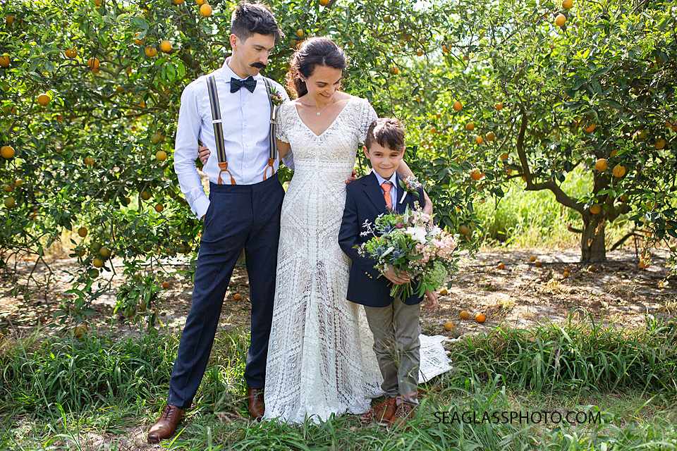 bride and groom look to their son as he holds his moms bouquet on their big day in Vero Beach Florida