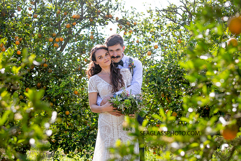 The Groom hugs his beautiful Bride in an orange grove in Vero Beach Florida