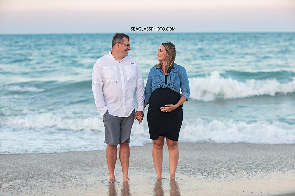 Expecting parents standing together on the beach at sunset in Vero Beach Florida