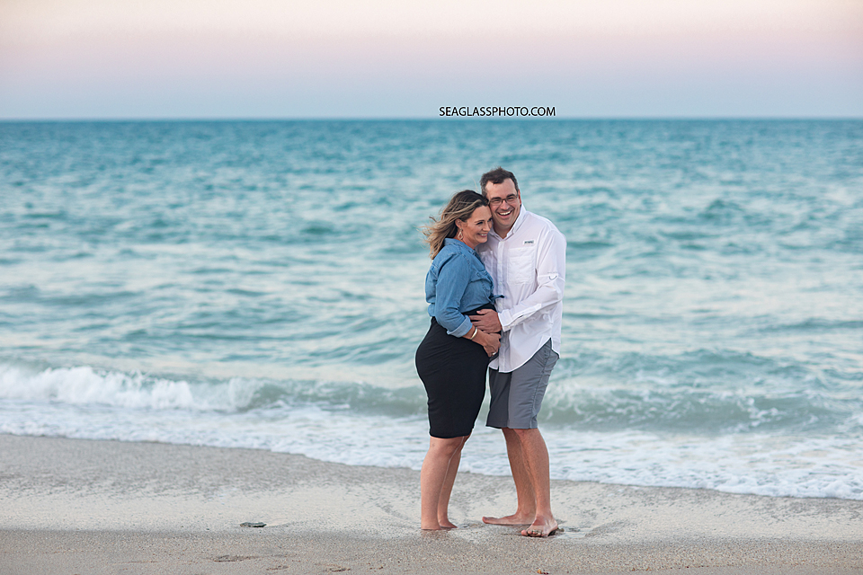 Expecting couple laughing together on the beach at sunset in Vero Beach Florida
