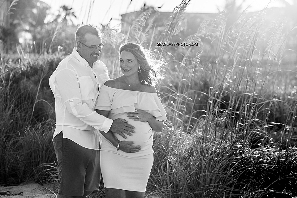 Black and White Expecting parents standing together on the beach at sunset in Vero Beach Florida
