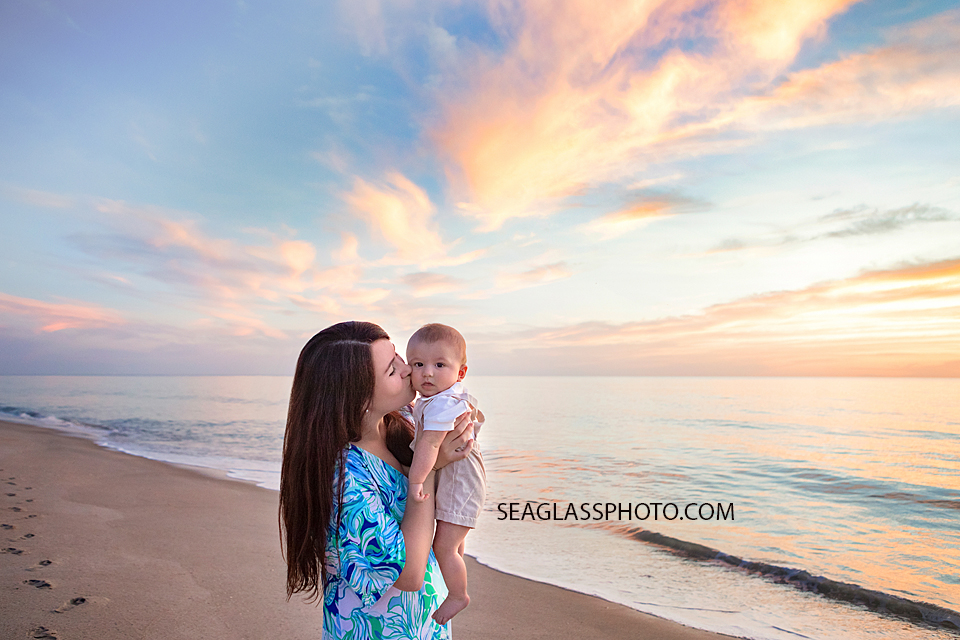 mom kissing baby at colorful sunrise on the beach at Disney Vero Beach Resort by Seaglass Photography