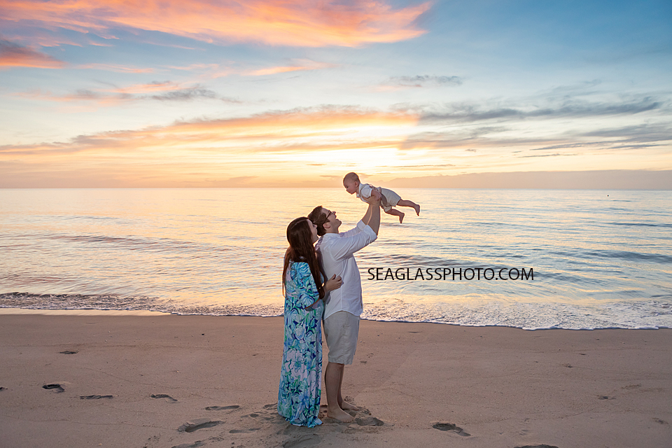 parents holding baby in the air at colorful sunrise on the beach at Disney Vero Beach Resort by Seaglass Photography