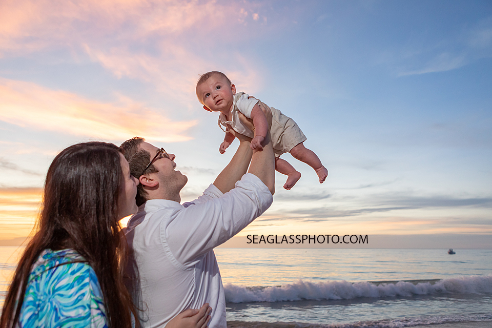 dad holding son up in the air at colorful sunrise on the beach at Disney Vero Beach Resort by Seaglass Photography