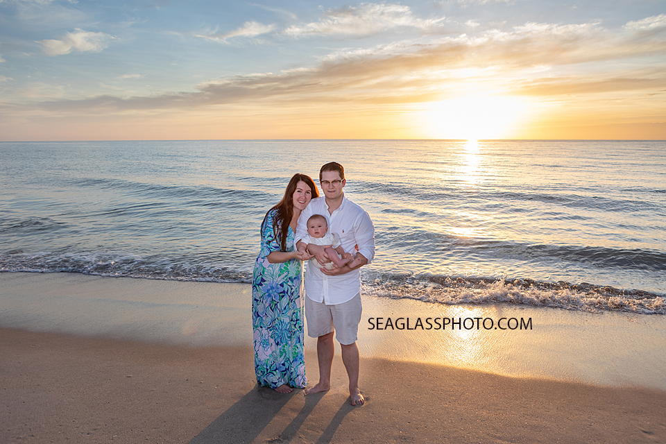 parents holding baby at colorful sunrise on the beach at Disney Vero Beach Resort by Seaglass Photography