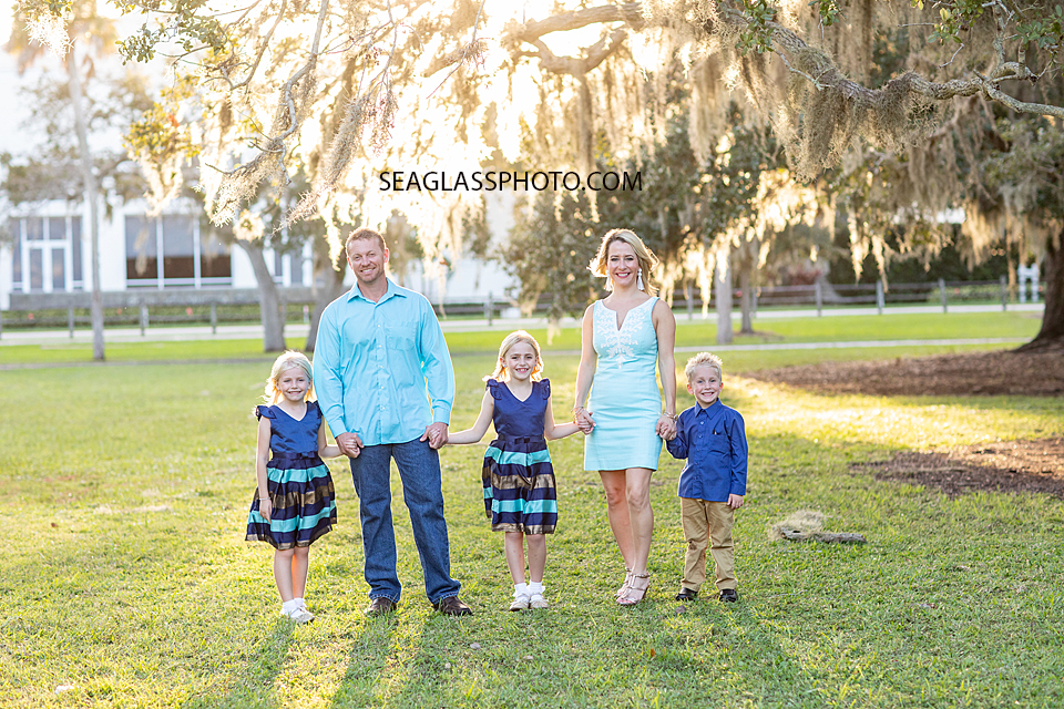 Family of five wearing shade of blue under an oak tree in vero beach florida