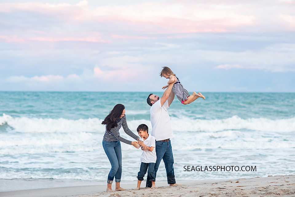 candid family photo at sunset with dad throwing daughter in the air wearing white and navy n Vero Beach Florida by Seaglass Photography at Disney Vero Beach Resort DVC