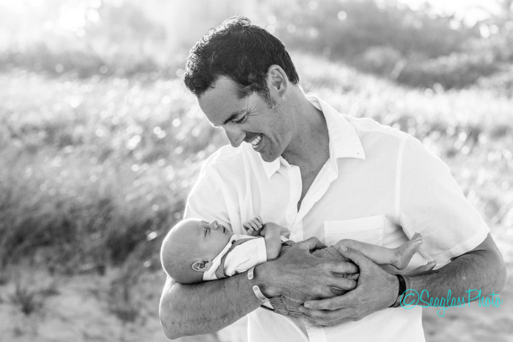 black and white photo of father holding newborn son on the sand dunes Vero Beach Florida Newborn Photographer
