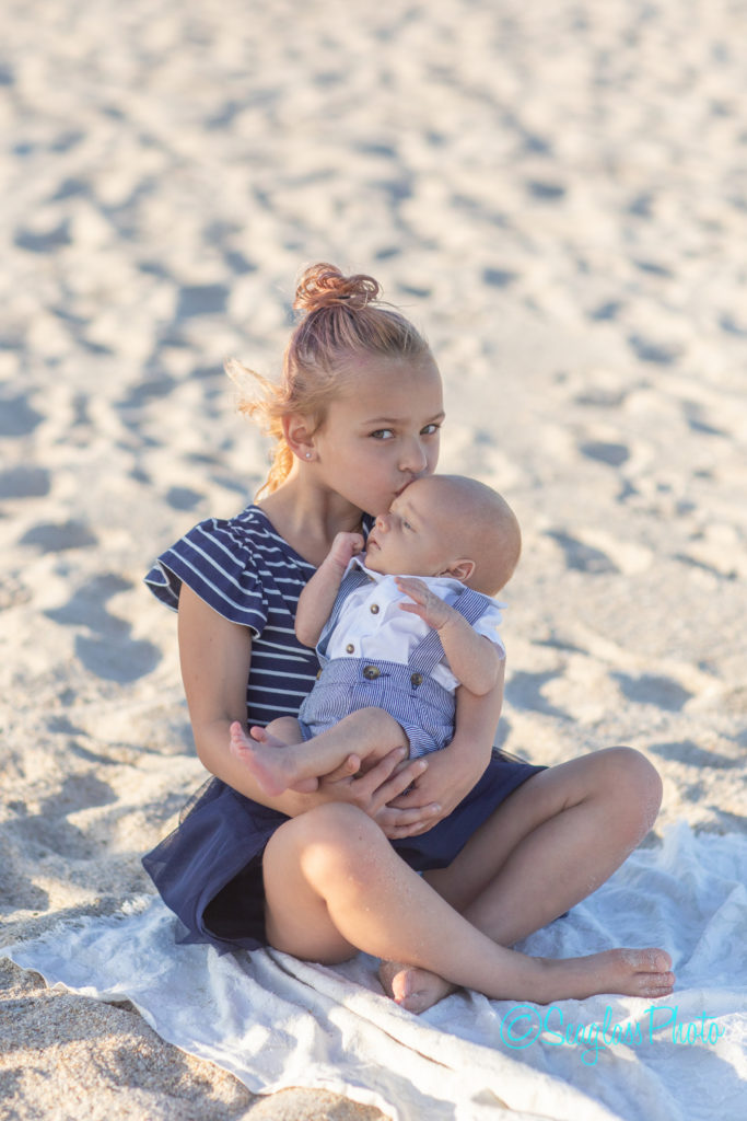 big sister holding newborn baby brother on the sand Vero Beach Florida Newborn Photographer