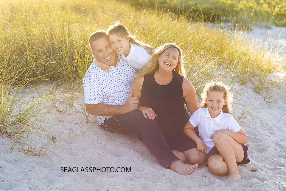 Family photo session sitting on the beach holding hands. Wearing navy, white