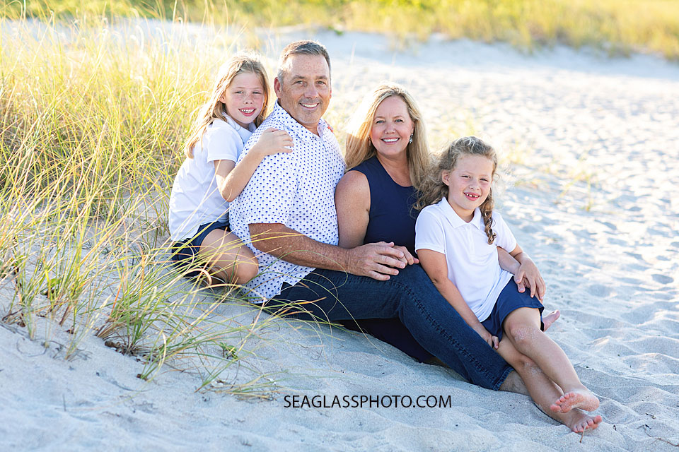 Family photo session sitting on the beach holding hands. Wearing navy, white in Vero Beach Florida