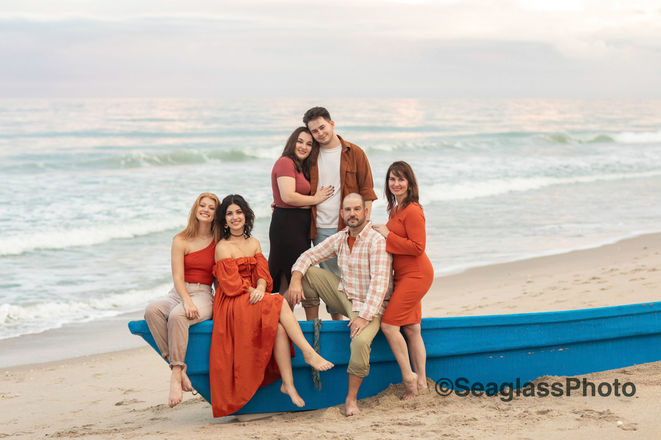 stunning portrait of family wearing orange sitting on a blue shipwreck family photoshoot in Vero Beach Florida