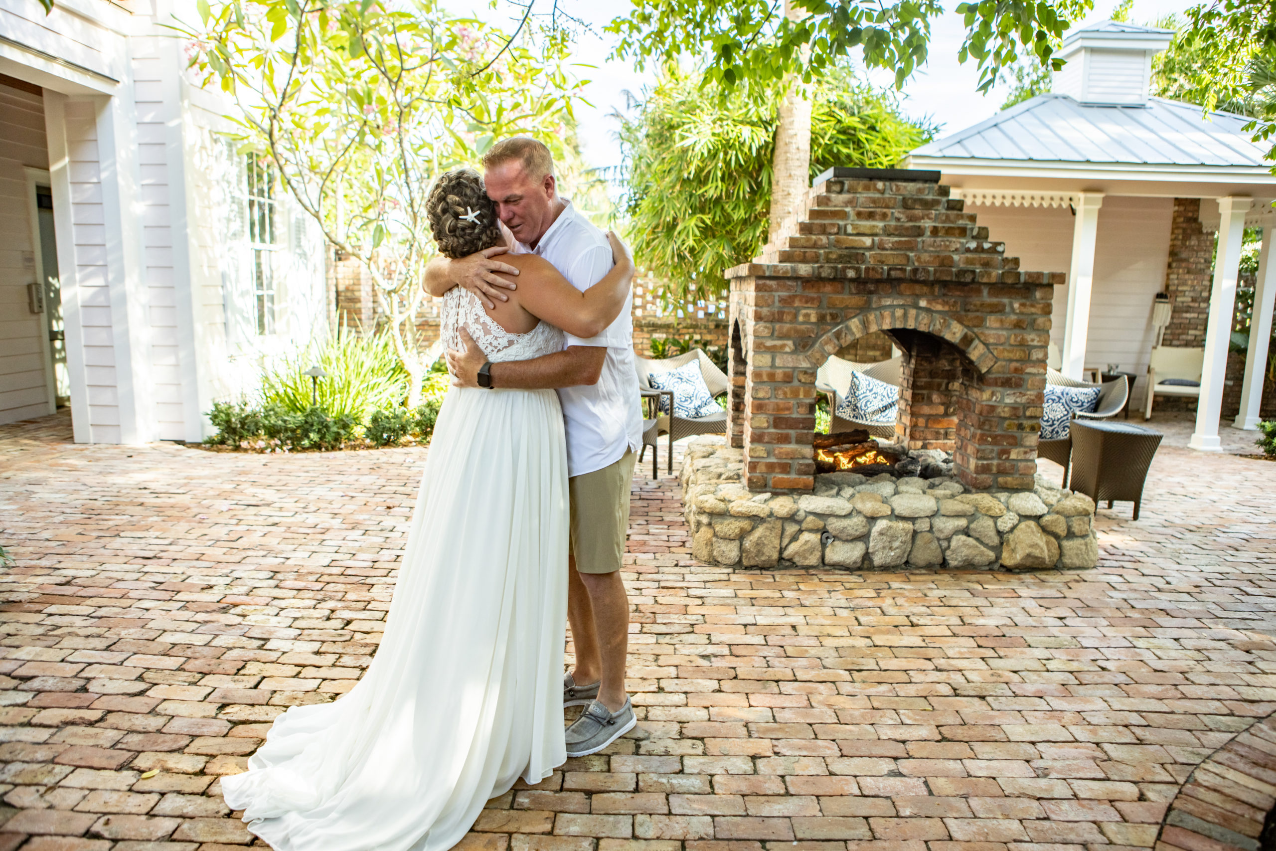 father and bride hugging by an outdoor fireplace