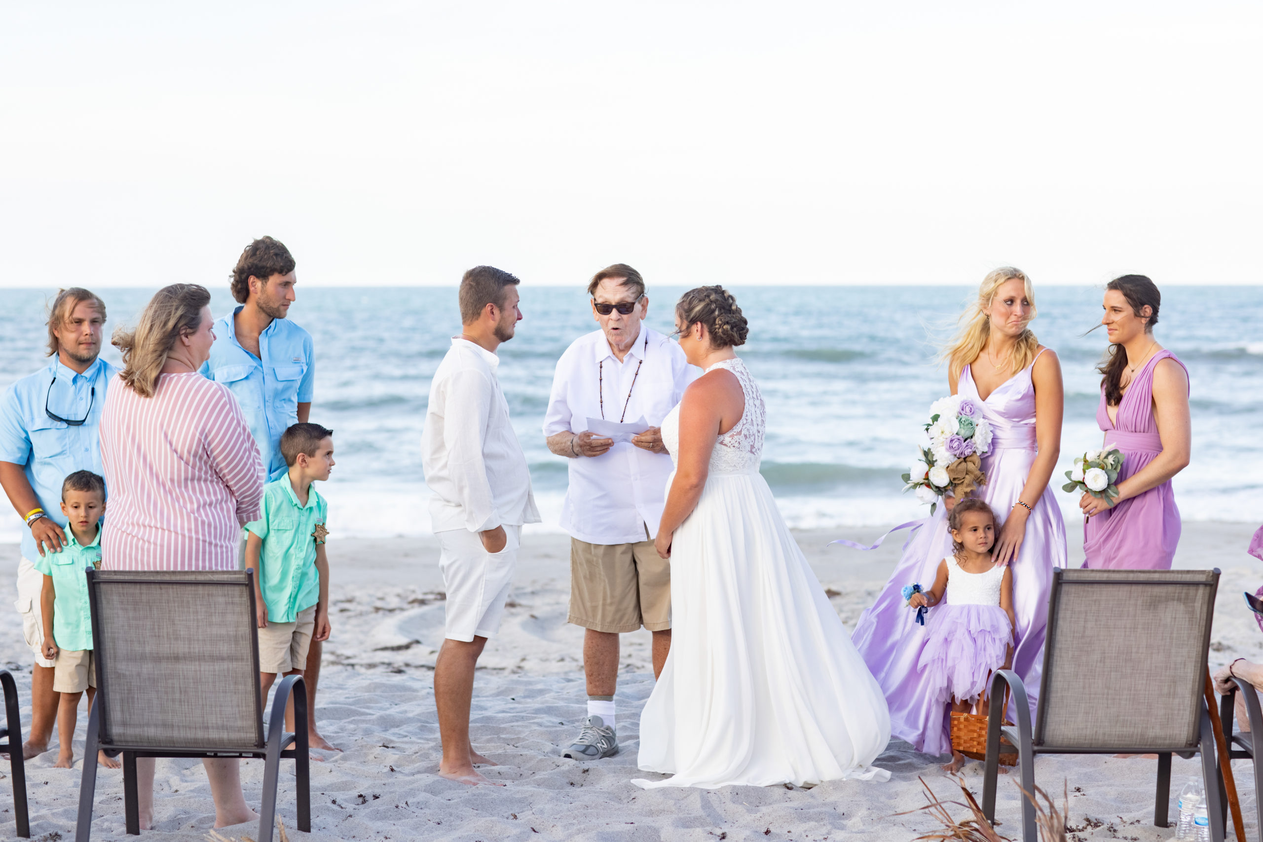 wedding ceremony on the beach with bridesmaids in purple and boys in blue