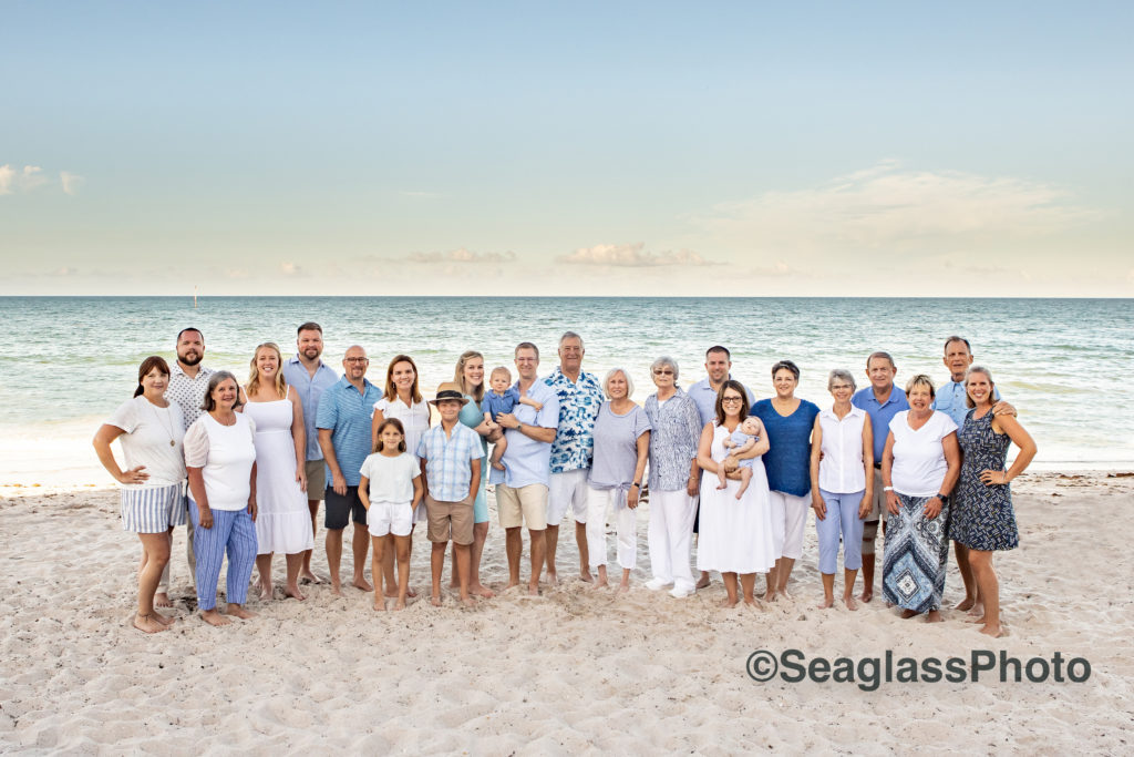 Group of 22 people wearing blue and white on the beach at sunset