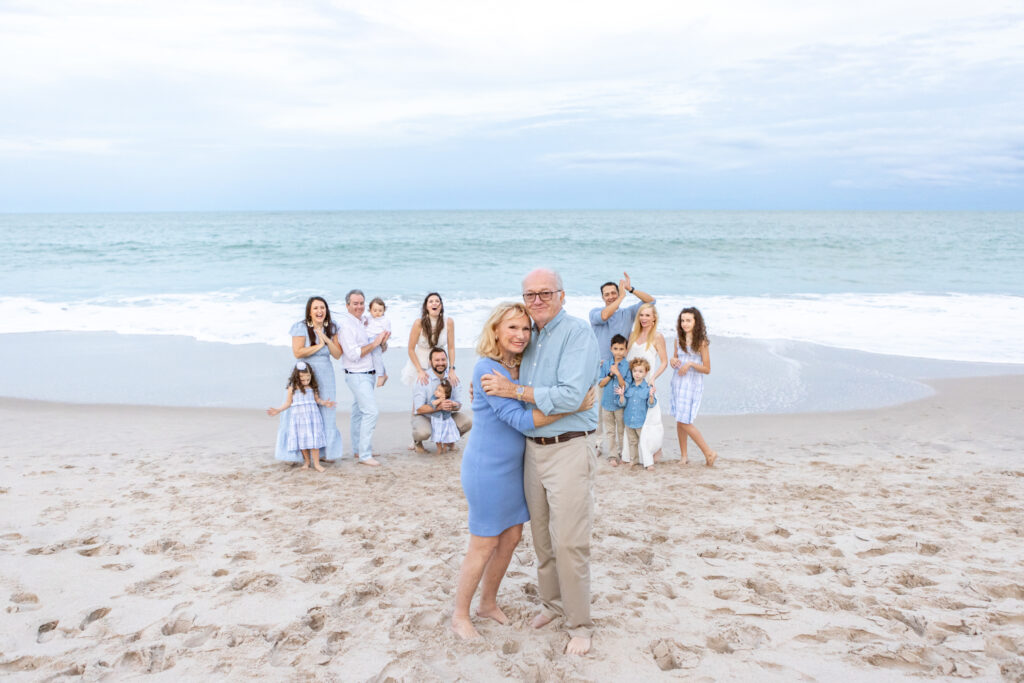 grandparents hugging on the beach with the family cheering them on in the background Vero Beach, Florida 32966