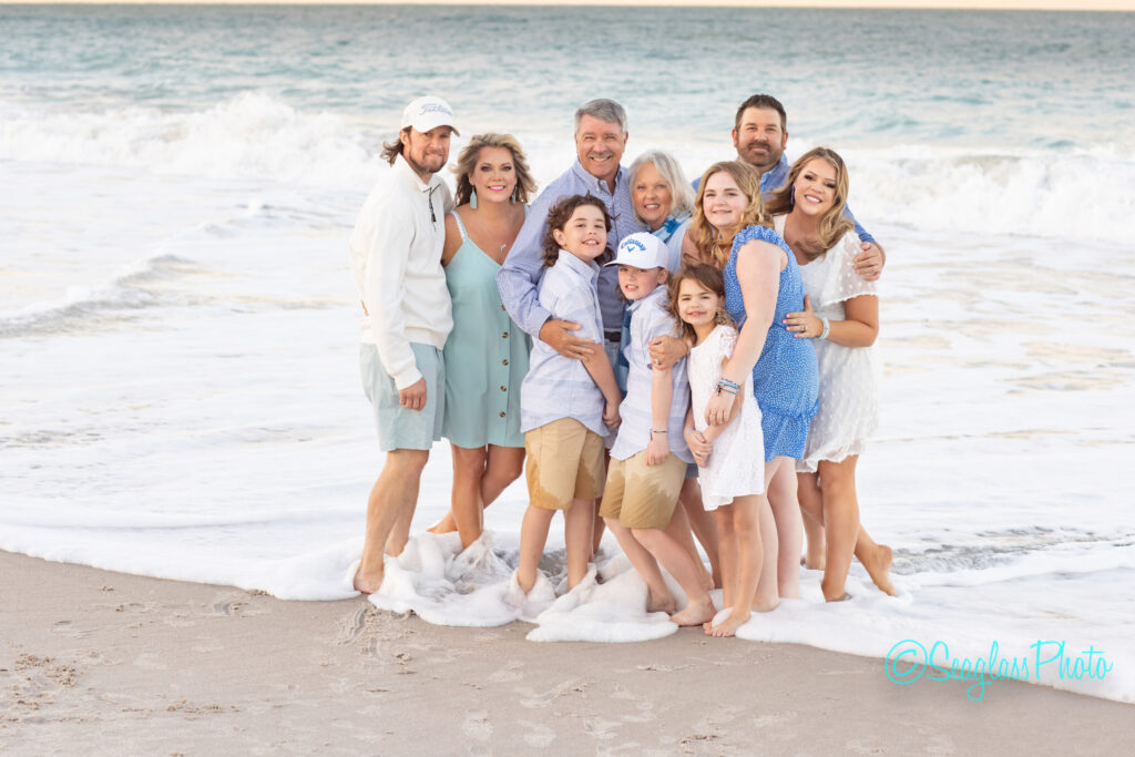 family hugging close together with the ocean waves crashing on their feet in Vero Beach Florida